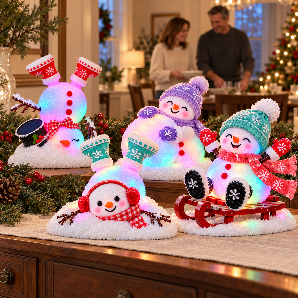 Four snowman decorations together on a Christmas dining-room counter with greenery, red berries and a family preparing a holiday meal in the background
