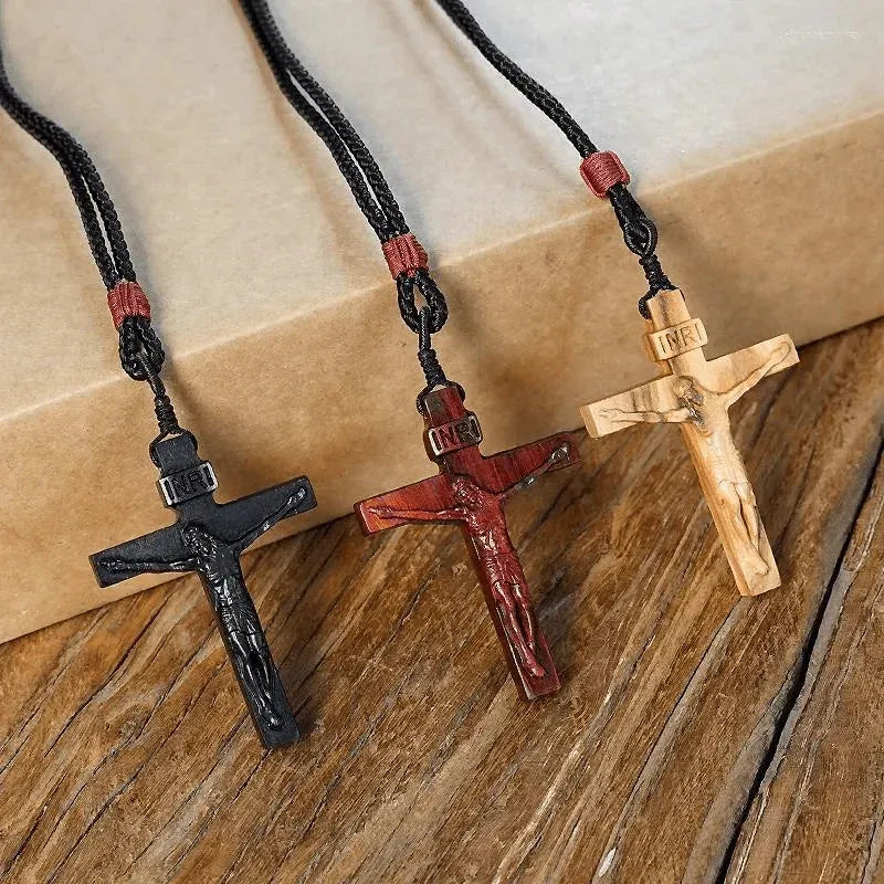 Three wooden crucifix necklaces in black, brown, and light finishes with their cords visible